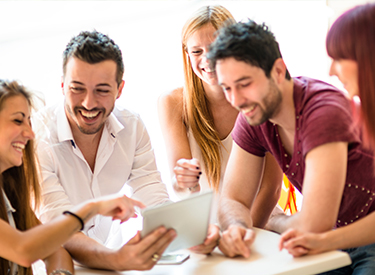 People sitting arround table looking at a tablet